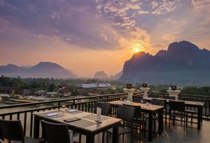 a restaurant with tables and chairs on a balcony with the sunset at Tulip Elegant Riverside Hotel in Vang Vieng