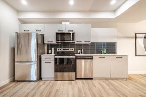 a kitchen with white cabinets and stainless steel appliances at Hotchlair Private Suite with Kitchen, Dining & Cozy Living Area in Calgary +15 photos