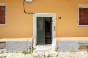a yellow building with a green and white door at Casa Petridou 2 in Corfu