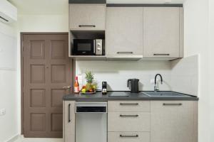 a kitchen with white cabinets and a sink and a door at Casa Petridou 2 in Corfu
