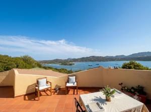 a balcony with tables and chairs and a view of the water at Domo s'Altura in Porto Rotondo