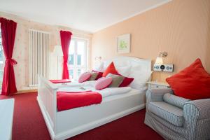 a bedroom with a white bed with red pillows and a chair at SaarlandTraum Weihermühle in Schmelz