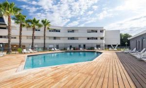 a swimming pool in front of a building with palm trees at Vacancéole - Le Terral - Montpellier Sud in Saint-Jean-de-Védas