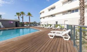 a deck with chairs and a swimming pool next to a building at Vacancéole - Le Terral - Montpellier Sud in Saint-Jean-de-Védas