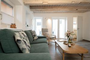 a living room with a green couch and a table at Haus 1805 Fehmarn in Fehmarn