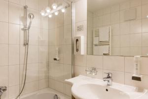 a white bathroom with a shower and a sink at Hotel Silbertal in Silbertal +48 photos