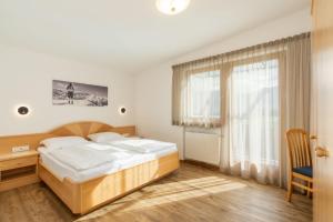 a bedroom with a bed and a desk and a window at B&B Garni Schorneck in Brunico
