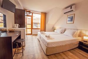 a bedroom with a bed and a desk and a kitchen at Guest House Elidis in Primorsko