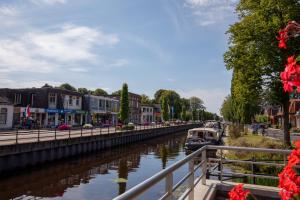 a boat on a river in a city at Hotel de Zon in Oosterwolde