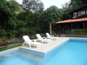 - un groupe de chaises blanches installées à côté de la piscine dans l'établissement Pousada Caminho das Candeias, à Lumiar