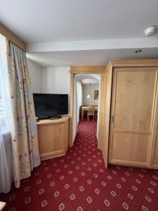 a room with a flat screen tv and a door at Hotel Silbertal in Silbertal
