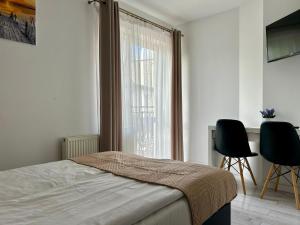 a bedroom with a bed and two chairs and a window at Perełka Bałtyku in Władysławowo