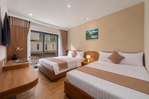 a hotel room with two beds and a television at RubyHome in Thôn Nguyệt Biều