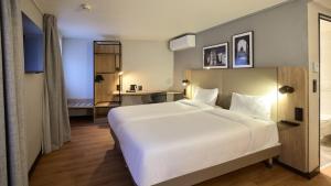 a bedroom with a large white bed and a bathroom at Campanile Lyon Centre - Berges du Rhône in Lyon