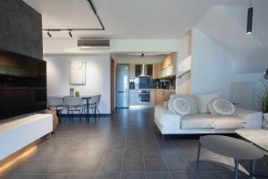a living room with a white couch and a table at Azure Residence Koumitsa in Nea Roda