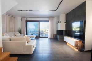 a living room with a white couch and a tv at Azure Residence Koumitsa in Nea Roda