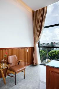 a chair and a table in a room with a window at Phố Núi 2 Hotel in Pleiku