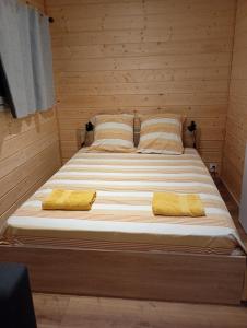 a bed in a wooden room with two yellow pillows at Studio chalet indépendant in Égletons