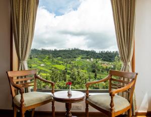 a room with two chairs and a window with a view at Western Valley Resorts Ooty in Ooty