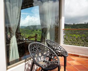 two chairs sitting on a balcony with a view at Western Valley Resorts Ooty in Ooty