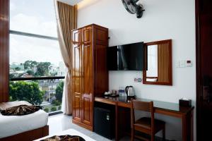 a bedroom with a desk and a bed and a window at Phố Núi 2 Hotel in Pleiku