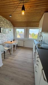 a kitchen and dining room with a table and two windows at Urban Style trifft Heideflair in Schneverdingen