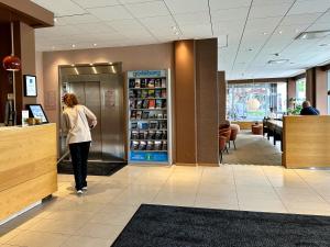 a woman walking through a store with a cash register at Spar Hotel Majorna in Gothenburg