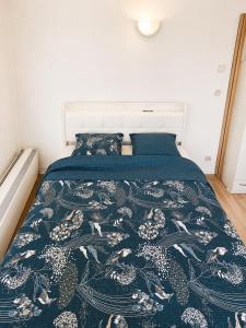 a bedroom with a bed with a blue comforter at Maisonnette en duplex avec Jardin-Babyfoot et Billard in Outreau