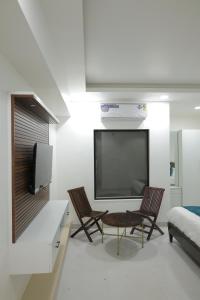 a living room with two chairs and a flat screen tv at Hotel Ashok Vatika in Māharjhari