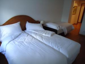 two beds in a room with white sheets and pillows at Relais Picaron in San Daniele del Friuli