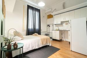 a bedroom with a bed and a table and a kitchen at Magdalena2 Street, Private rooms in Madrid