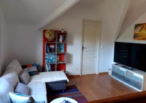 a living room with a white couch and a tv at Ilodays in La Plaine des Cafres