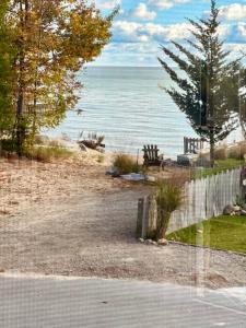 a view of a beach with a bench and the ocean at The SeveraLena, your Tawas Point destination! in East Tawas