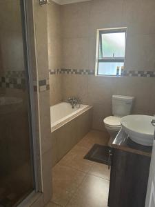 a bathroom with a tub and a toilet and a sink at Bouleigh in Kempton Park +19 photos