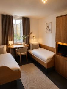 a hotel room with two beds and a desk at Hotel zur Linde in Berghausen