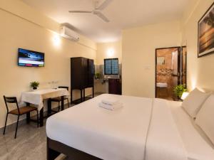 a room with a white bed and a table and chairs at Coutinho Guest House in Panaji +4 photos