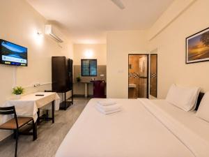 a hotel room with a white bed and a table at Coutinho Guest House in Panaji
