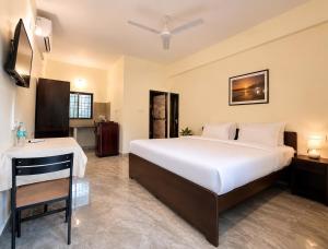 a bedroom with a large white bed and a desk at Coutinho Guest House in Panaji