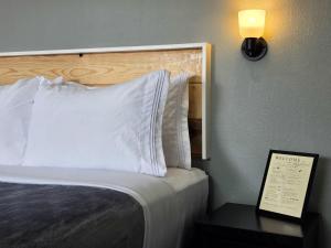 a bed in a hotel room with a white pillow at Skyliner Motel in Stroud