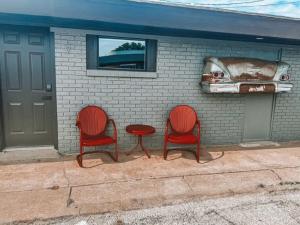 two red chairs and a table in front of a building at Skyliner Motel in Stroud