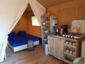 a room with a bed and a kitchen in a tent at De Tien Heugten in Schoonloo