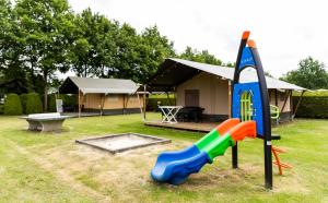 a playground with a slide in front of a tent at De Tien Heugten in Schoonloo