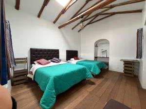 two beds in a room with green sheets at Auquis Hostel in Cusco