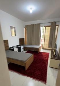 a living room with two beds and a red rug at Alreem building in Abu Dhabi