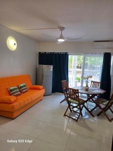 a living room with an orange couch and a table at Studio ALIZÉS in Le Moule