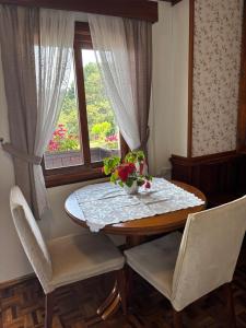 a dining room table with a vase of flowers on it at Hospedaria Gãstehaus Enzian in Treze Tílias