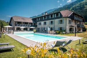 a hotel with a swimming pool in front of a building at Hôtel Restaurant Le Madame in La Ferrière