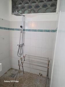 a shower in a white tiled bathroom at Studio ALIZÉS in Le Moule +2 photos