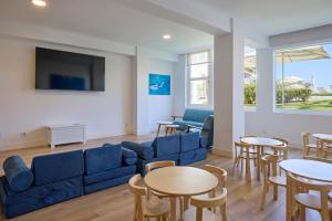 a living room with a blue couch and tables and chairs at Universal Hotel Castell Royal in Canyamel