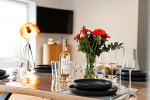 a table with a bottle of wine and a vase of flowers at App Ankerplatz in Morsum +26 photos